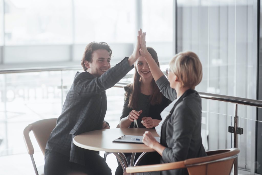 Happy successful business team giving a high fives gesture as they laugh and cheer their success